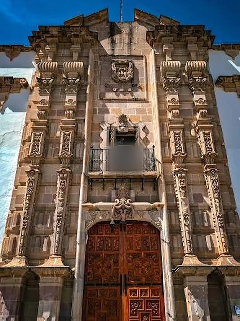 Portada barroca de cantera con estípites, balcón y escudo