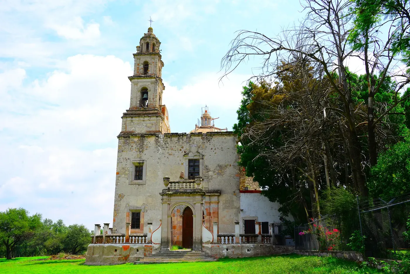 Templo virreinal antiguo de una sola torre, entre árboles